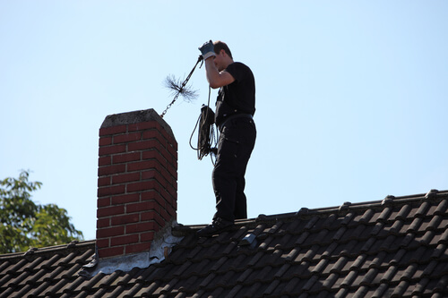 chimney sweep inspecting and cleaning the top of a chimney