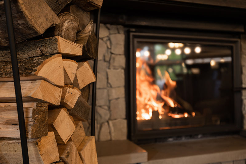 stack of wood in front of a burning fireplace 